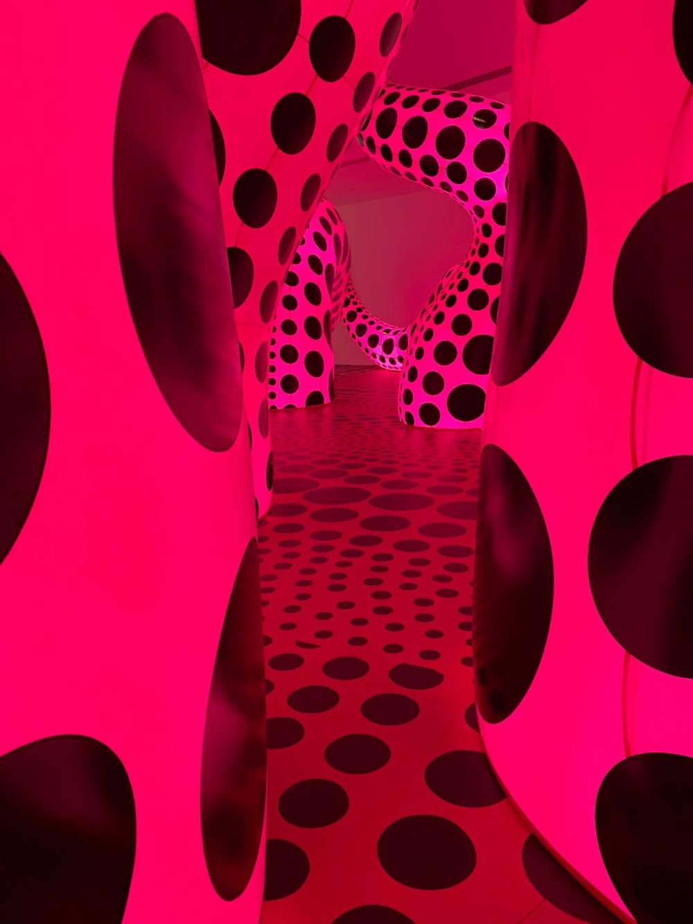נקודות שחורות על רקע ורוד בביקור בתערוכה של האומנית קוסאמה