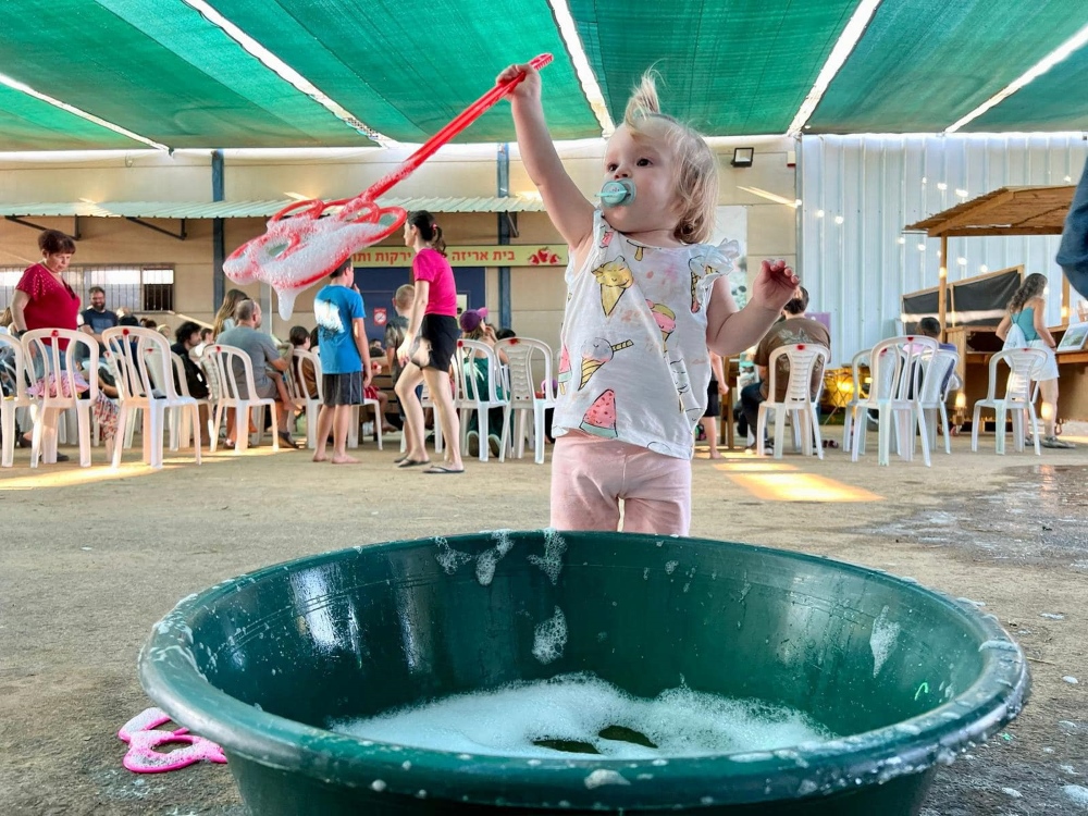 ילדה מתוקה משחקת בבועות סבון באירוע הפנינג סביבה וקיימות