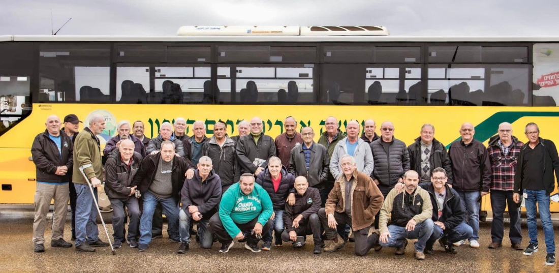 צוות מערך ההיסעים של דרום השרון בתמונה קבוצתית על רקע אוטובוס הסעות