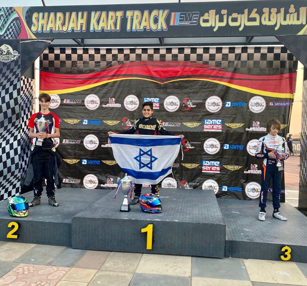 גיא אלבז מירחיב על הפודיום עם דגל ישראל באליפות הקארטינג בדובאי