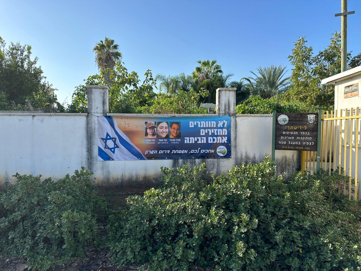 תמונה של כרזה למען שחרור החטופים תלויה בכניסות ליישובי המועצה השונים