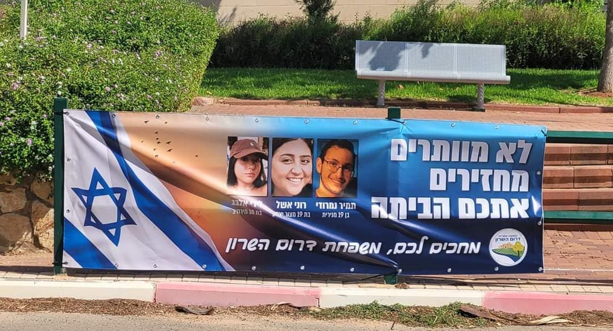 תמונה של כרזה למען שחרור החטופים תלויה בכניסות ליישובי המועצה השונים