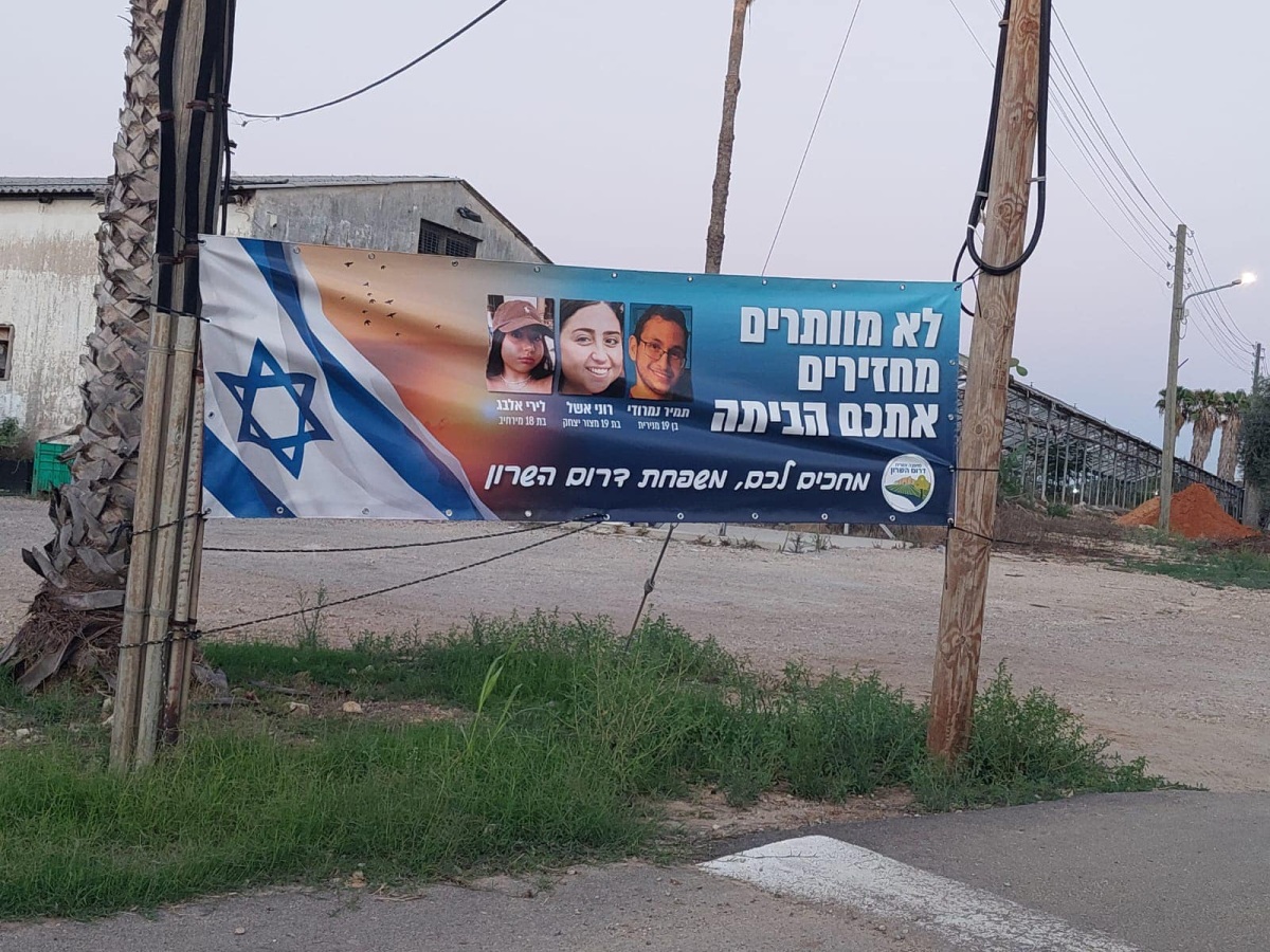 תמונה של כרזה למען שחרור החטופים תלויה בכניסות ליישובי המועצה השונים